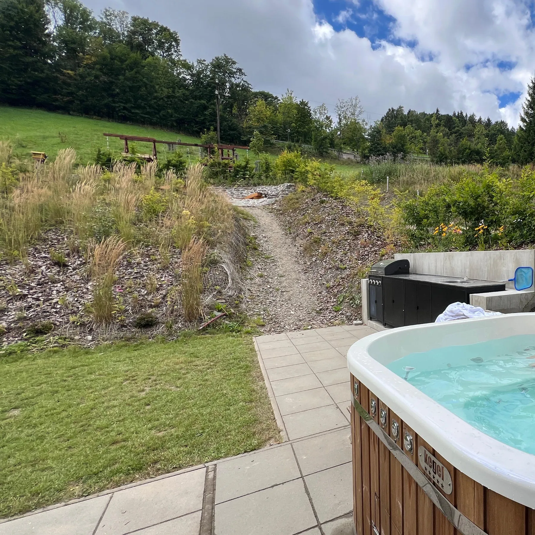 Hot tub on the paved terrace, garden and meadow above